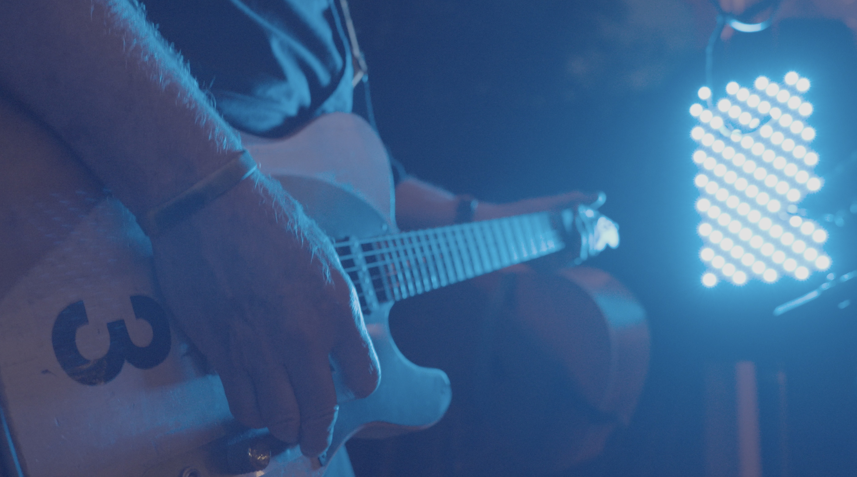 Close-up of Mike McLeod's guitar under blue stage lights